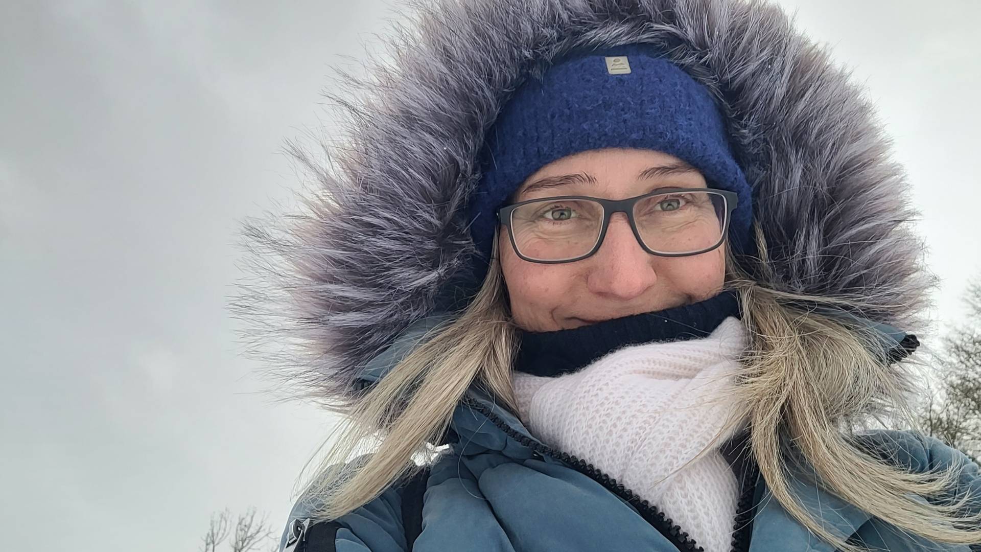 warm eingepackte Frau im Winter, im Hintergrund grauer Himmel