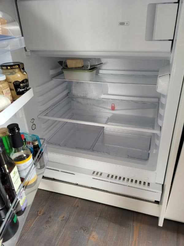 Blick in einen halbleeren Kühlschrank mit Butter, Senf und Ölflaschen im Türfach