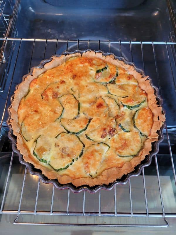 Frisch gebackene Zucchini-Quiche auf einem Kuchengitter im Backofen